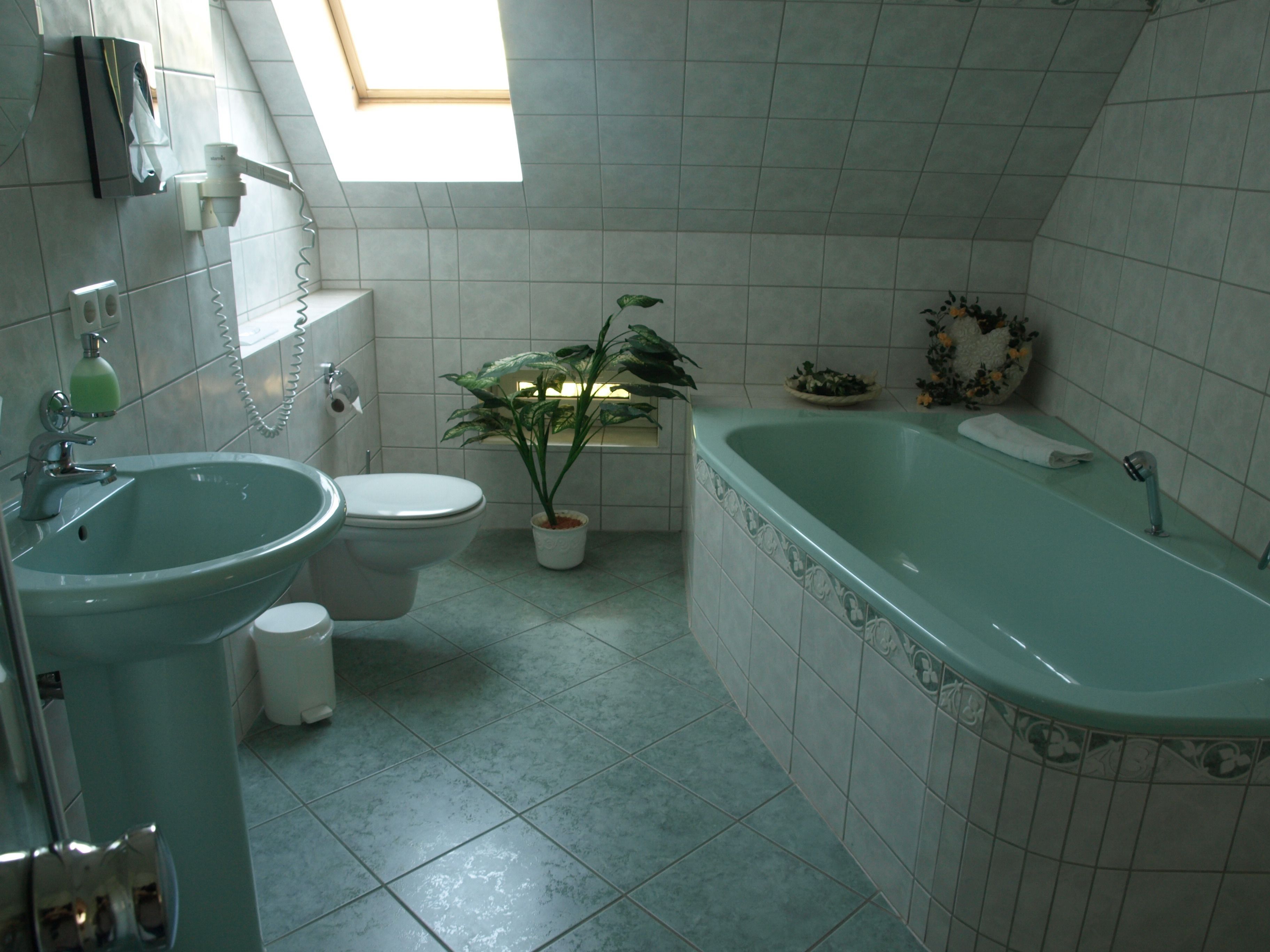 Ein Badezimmer mit Waschbecken, Toilette, Badewanne und einem Oberlicht.