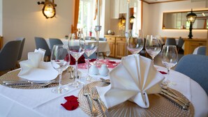 Ein Esstisch ist elegant mit feinem Porzellan, Besteck und Weingläsern gedeckt, was auf ein formelles Dinner hindeutet.