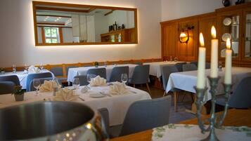 Un comedor con mesas dispuestas para una comida, un espejo grande en la pared y un candelabro con velas.