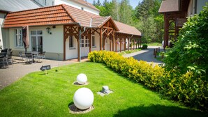 Ein Gebäude mit Ziegeldach, Außenbereich mit Sitzgelegenheiten und einer Rasenfläche mit kugelförmigen Dekorationen.