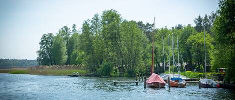 A calm lake with boats docked at a pier, surrounded by lush greenery.