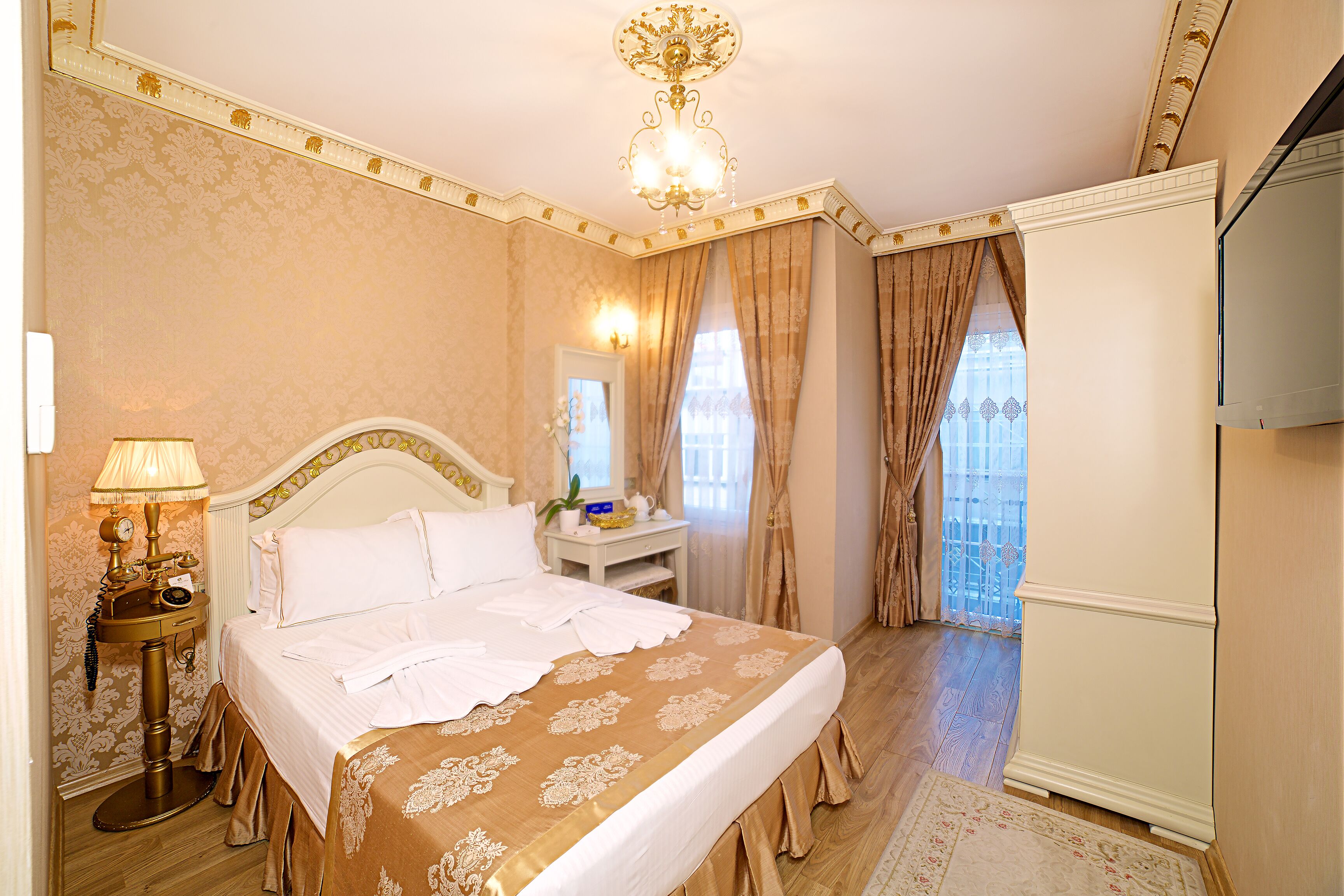 A hotel room with a large bed, a bedside table with a lamp, a dresser, and a television.