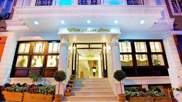 Das White House Hotel mit einem prunkvollen Eingang, Säulen und einer gut beleuchteten Fassade.