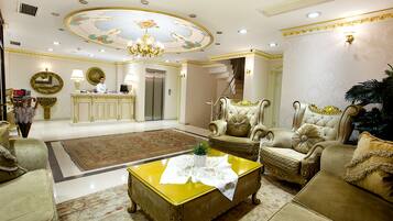 Un vestíbulo lujoso con decoración elaborada, un mostrador de recepción y zonas de estar elegantes.
