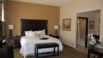 A hotel room with a large bed, bedside tables, a desk, and a chair.