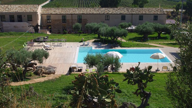Una villa con piscina, mobiliario de exterior y jardín.