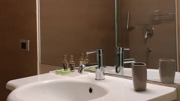A bathroom with a white sink, a mirror, and a shower.