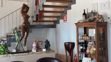 A spacious living area with a wooden ceiling, a spiral staircase, and a collection of decorative items including a statue, chairs, and a wooden cabinet.