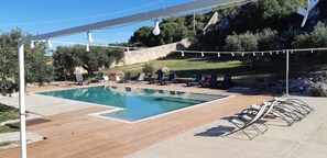A swimming pool with lounge chairs and a pergola with string lights. - Relais Casa Mirabile (Menfi)