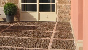 A stone building with a large arched window and a potted plant beside it. - Relais Casa Mirabile (Menfi)