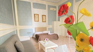 A room with a bed, a sofa, a small table, and a vase with flowers. - Dimora Annulina B&B (Palermo)