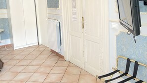 A room with a tiled floor, a white wardrobe, a radiator, a closed door, and a TV mounted on the wall. - Dimora Annulina B&B (Palermo)