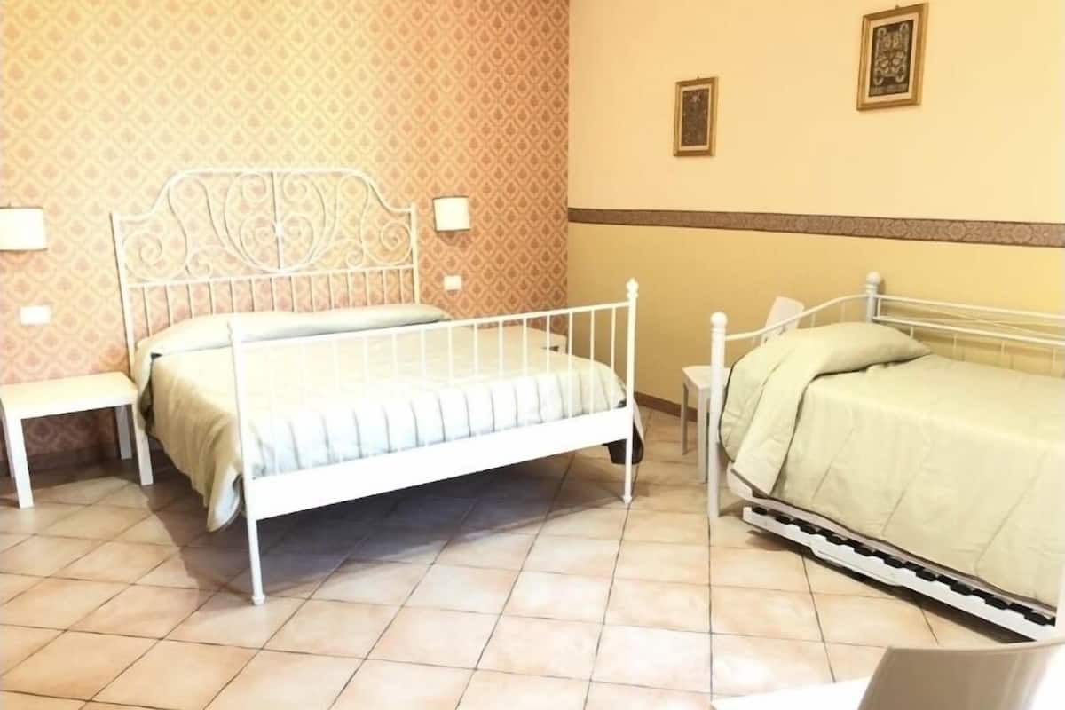 A room with two beds, a bench, and a small table.