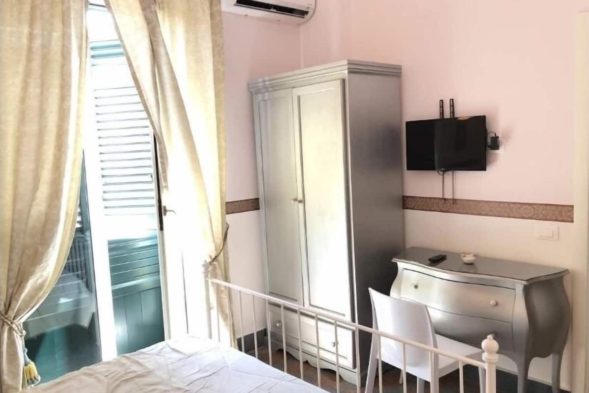 A hotel room with a bed, a wardrobe, a desk, a chair, and a television.
