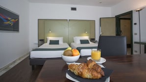 A hotel room with two beds, a dining table with breakfast, and a mirror on the wall.