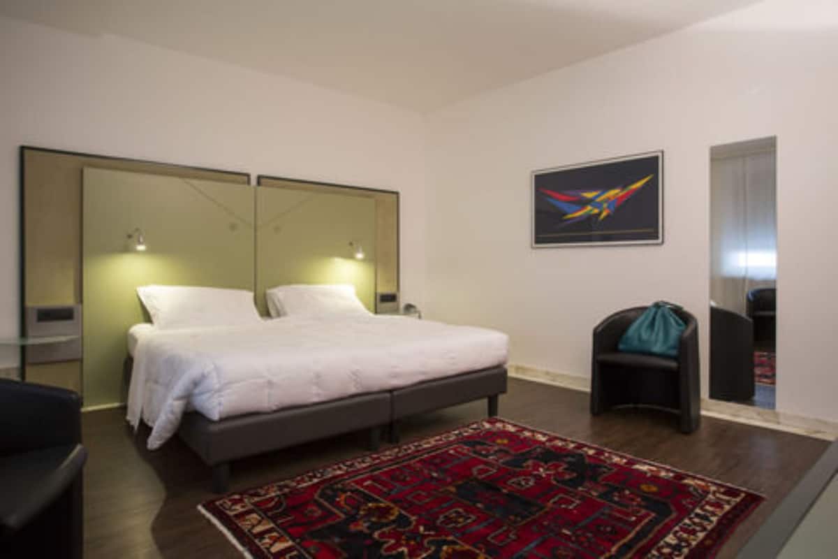 Ein Schlafzimmer mit Bett, Spiegel, Stuhl und Teppich.
