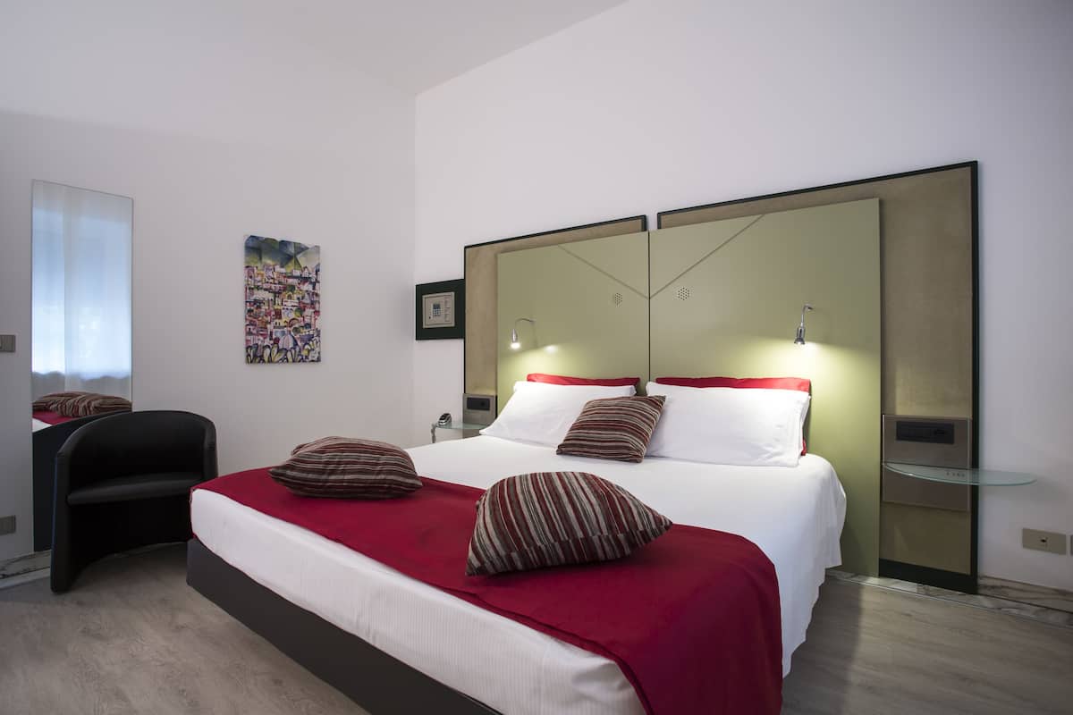 Ein modernes Hotelzimmer mit einem großen Bett, einem Schreibtisch und einem Spiegel.