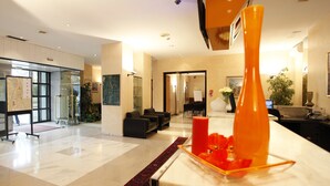A spacious lobby with a marble reception desk, a red vase, and a map on the wall.