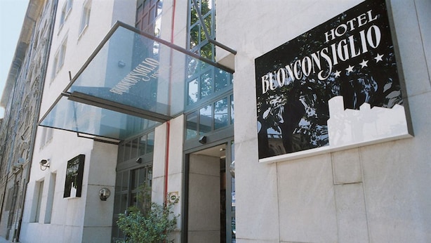 The entrance to Hotel Bellagio with a glass canopy and a signboard.