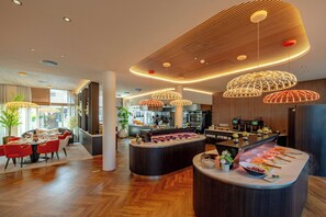 Un restaurante moderno con barra central, suelo de madera y luminarias contemporáneas.