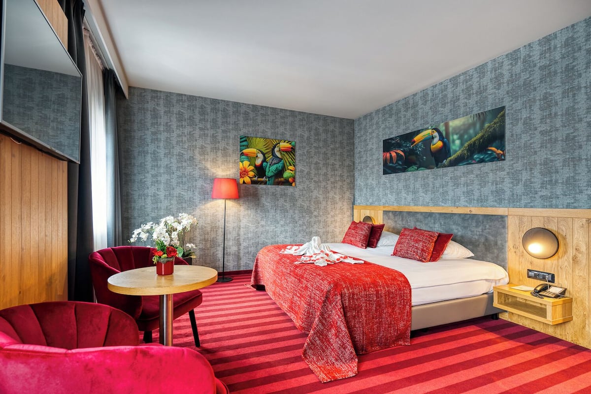 Een hotelkamer met een bed, een bureau, een stoel, een lamp en kunst aan de muren.