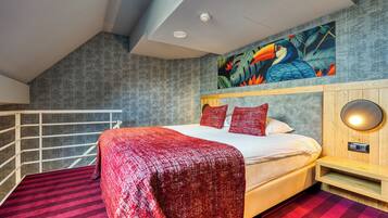 Un dormitorio moderno con una cama grande, ropa de cama roja, cabecera de madera, una lámpara de pared y un mural tropical.