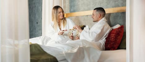 A couple in a hotel room with a bed, pillows, and a headboard.
