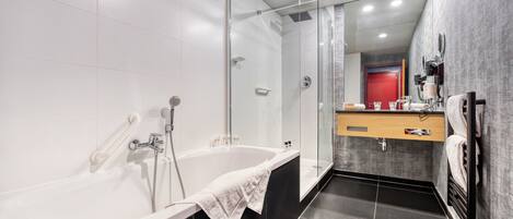 Un baño moderno con una bañera grande, cabina de ducha con paredes de vidrio y tocador con espejo.