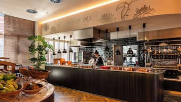 Una cocina moderna con un chef preparando comida, una zona de bar y una encimera con fruteros.