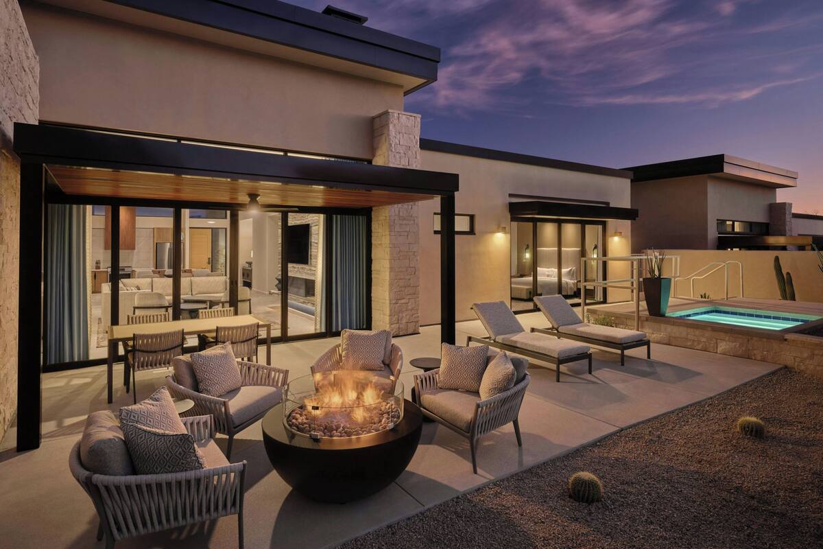 A modern outdoor patio with a fire pit, lounge chairs, and a swimming pool.