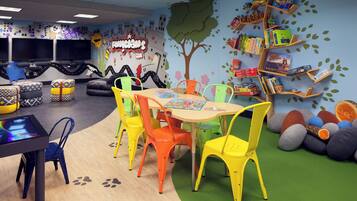 A children's playroom with colorful chairs, a table, and a bookshelf filled with books.