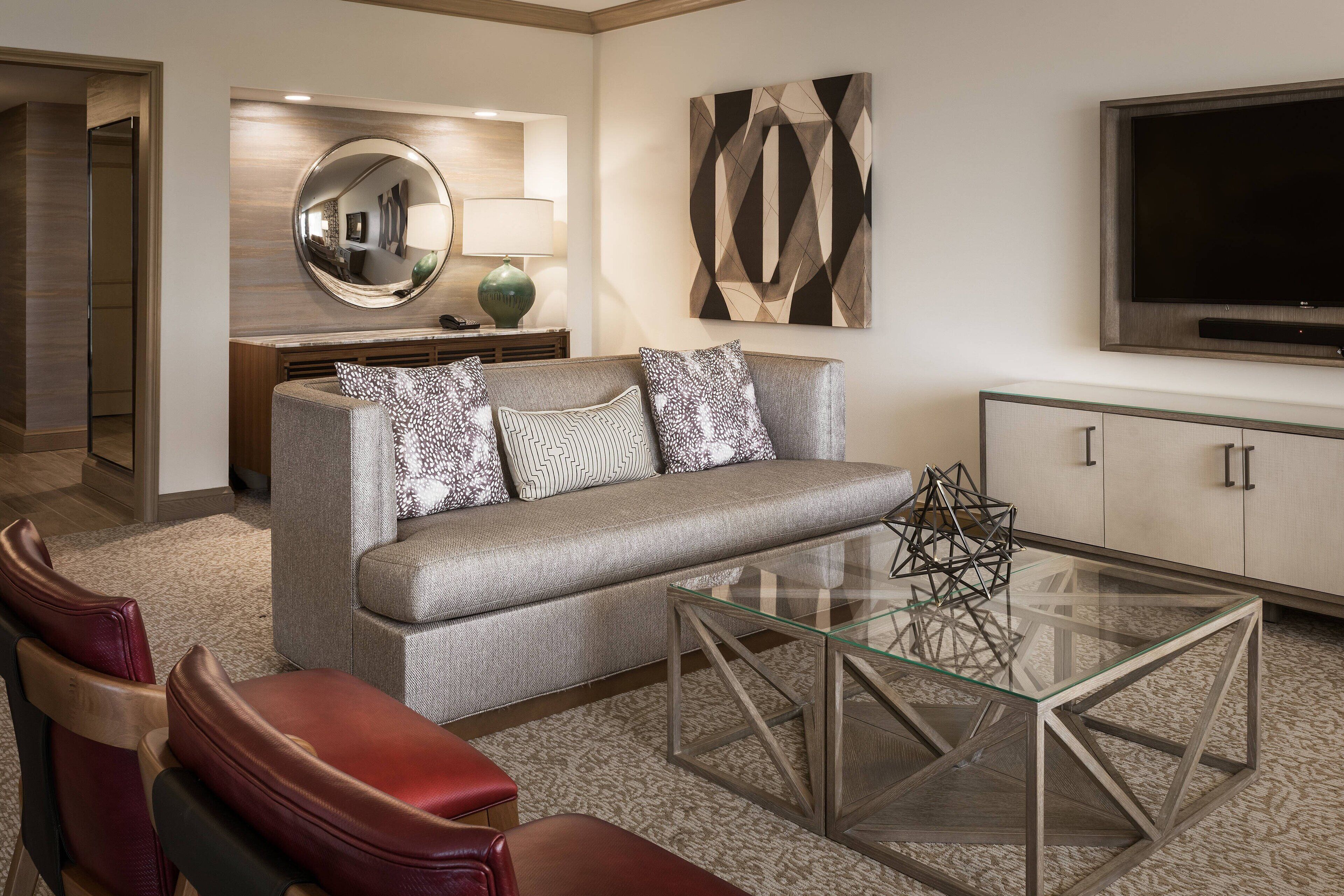 Un salon moderne avec un canapé, une table basse en verre et des fauteuils en cuir.