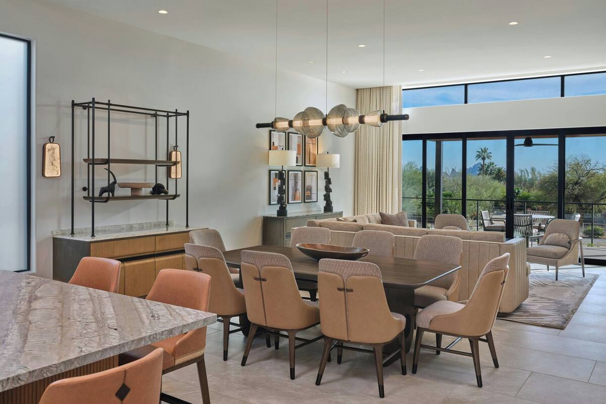 A modern dining area with a large table, multiple chairs, and a decorative light fixture.