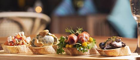 A wooden table with a variety of appetizers arranged on small bread pieces.