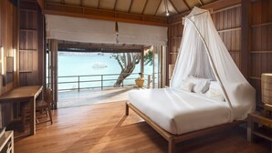 A wooden room with a bed, a table, and a view of the sea. - Haadtien Beach Resort (Koh Tao)