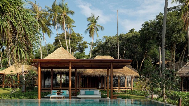 A poolside area with a thatched-roof structure, a lounge with seating, and a view of palm trees. - Haadtien Beach Resort (Koh Tao)