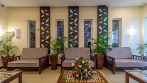 A lobby with three sofas, a coffee table with a floral centerpiece, and potted plants. - Prideinn Mombasa City (Mombasa)
