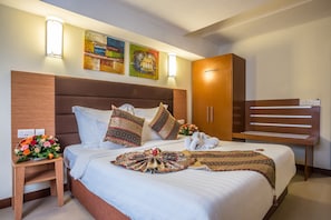A hotel room with a large bed, wooden headboard, decorative pillows, a bedside table with a flower arrangement, and artwork on the wall. - Prideinn Mombasa City (Mombasa)