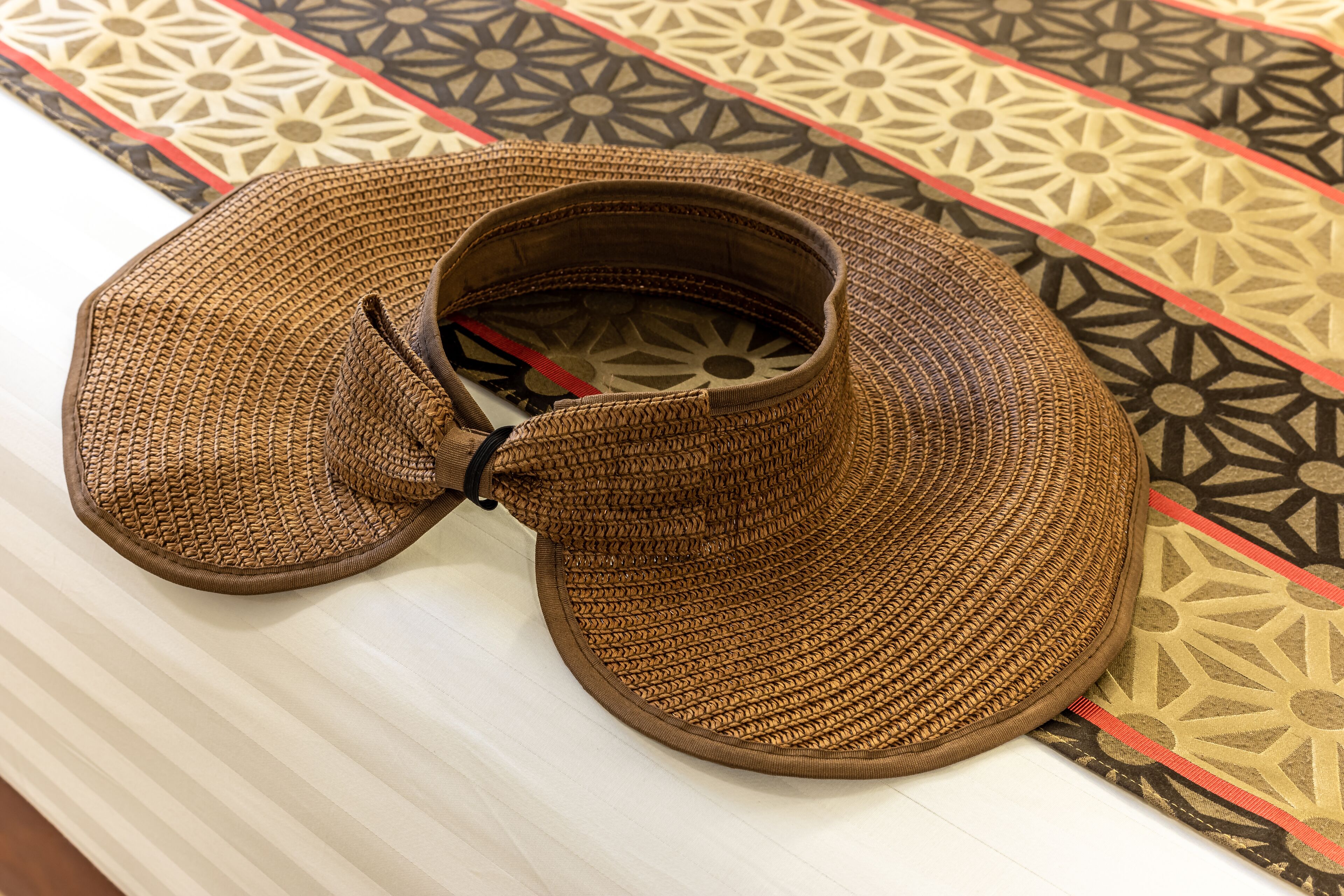 A pair of woven sandals with a strap and a buckle, placed on a striped surface.