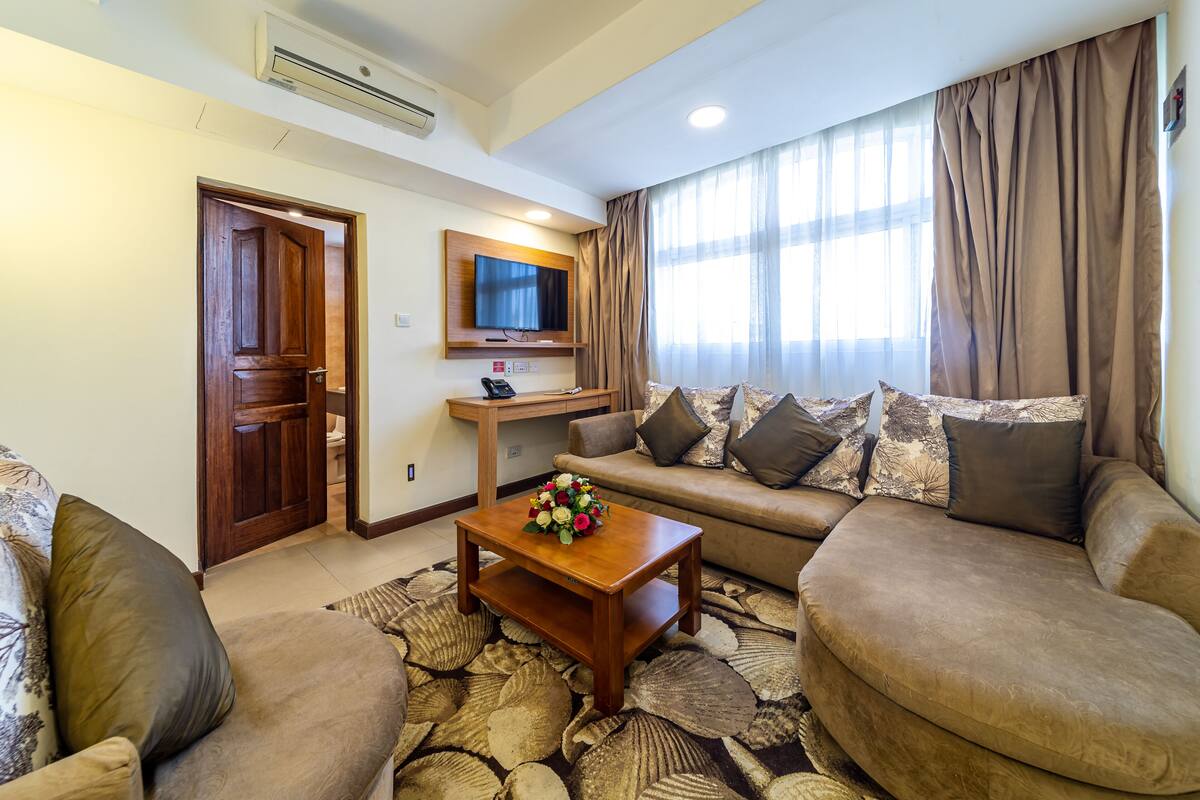 A living room with a sofa, a coffee table, a TV, and a door.