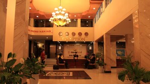 A reception area with a chandelier, reception desk, and potted plants. - Princes Catba Hotel (Hai Phong)