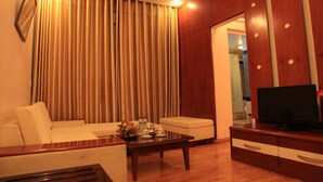 A living room with a sofa, coffee table, and TV stand. - Princes Catba Hotel (Hai Phong)