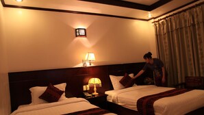 A hotel room with two beds, a nightstand with a lamp, a wall clock, and a curtain. - Princes Catba Hotel (Hai Phong)