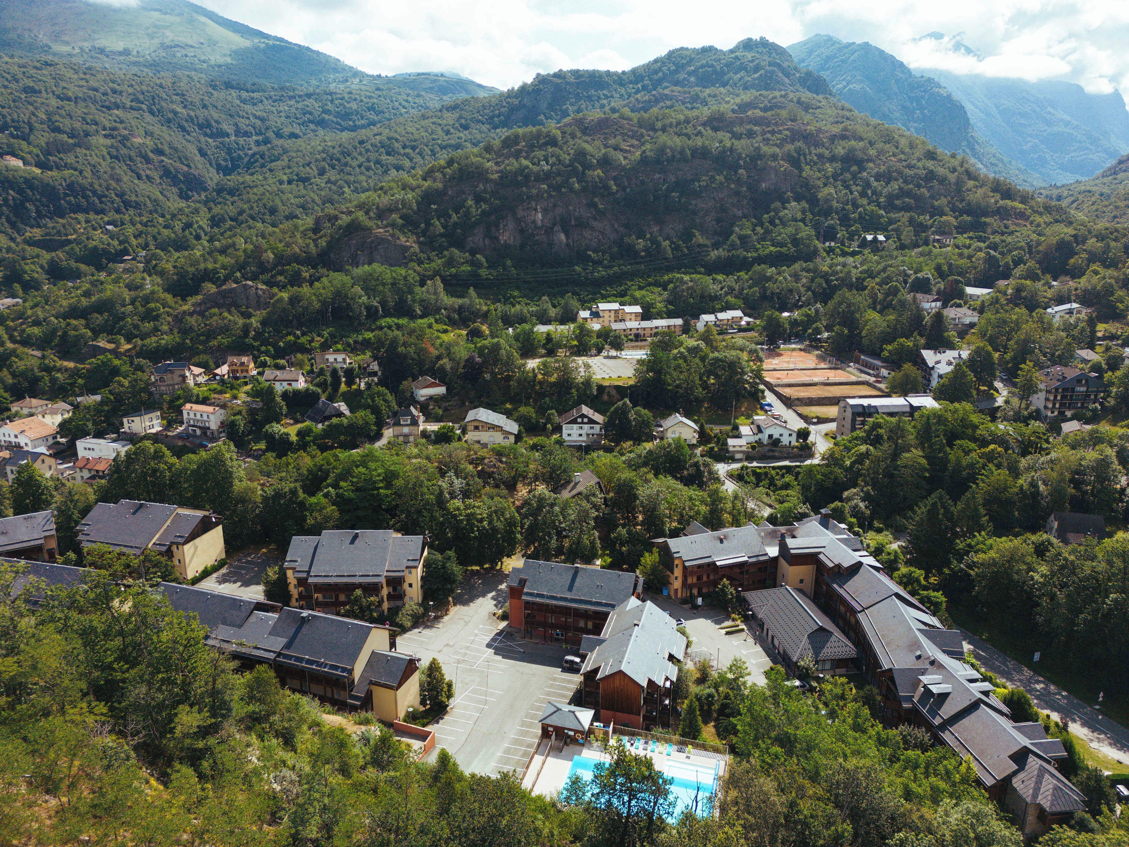 A residential area with houses, a swimming pool, and a mountainous backdrop.