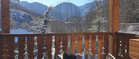 Una terraza de madera con vistas a montañas nevadas y árboles.