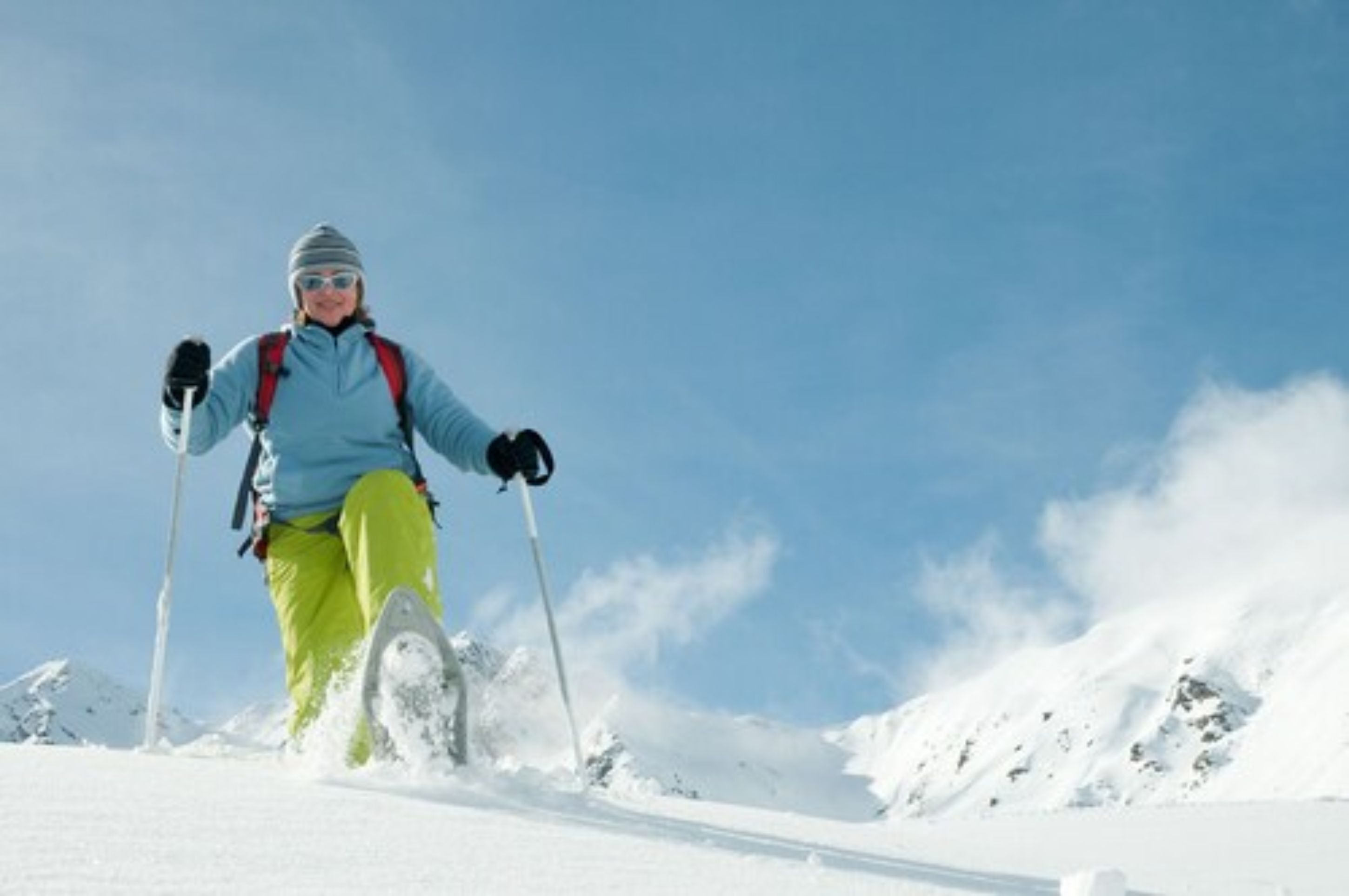 A person skiing on a snowy slope with a clear sky in the background.