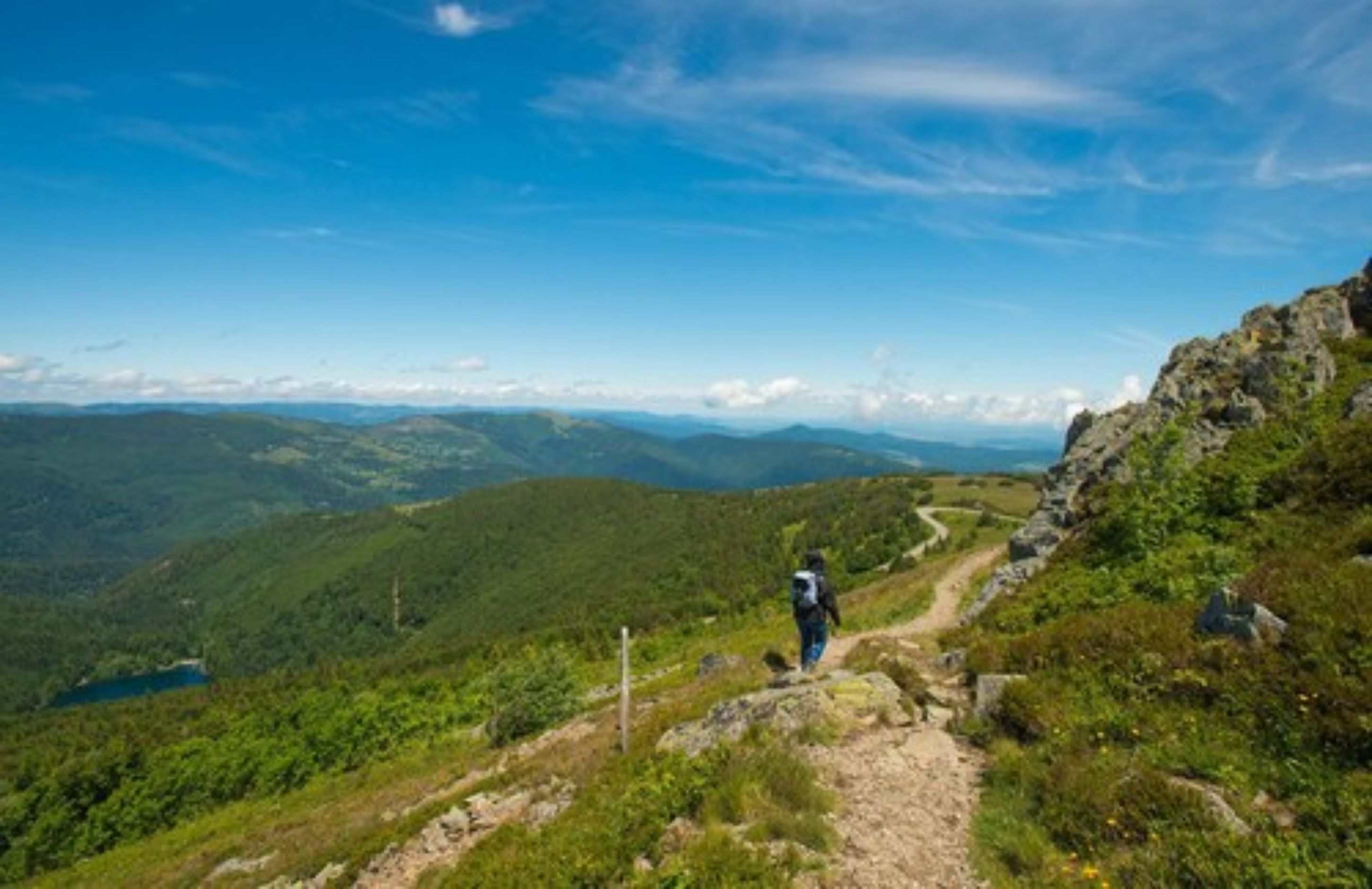Un excursionista en un sendero de montaña con vistas despejadas del paisaje circundante.