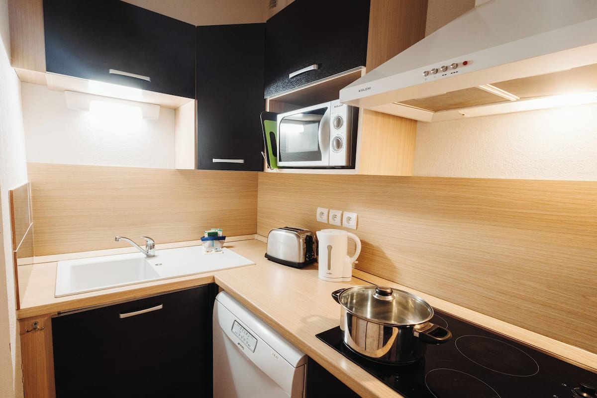 A compact kitchen with a dishwasher, a microwave, a toaster, and a kettle.