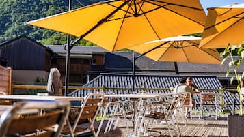 Un área de comedor al aire libre con sombrillas amarillas, mesas de madera y sillas de metal.