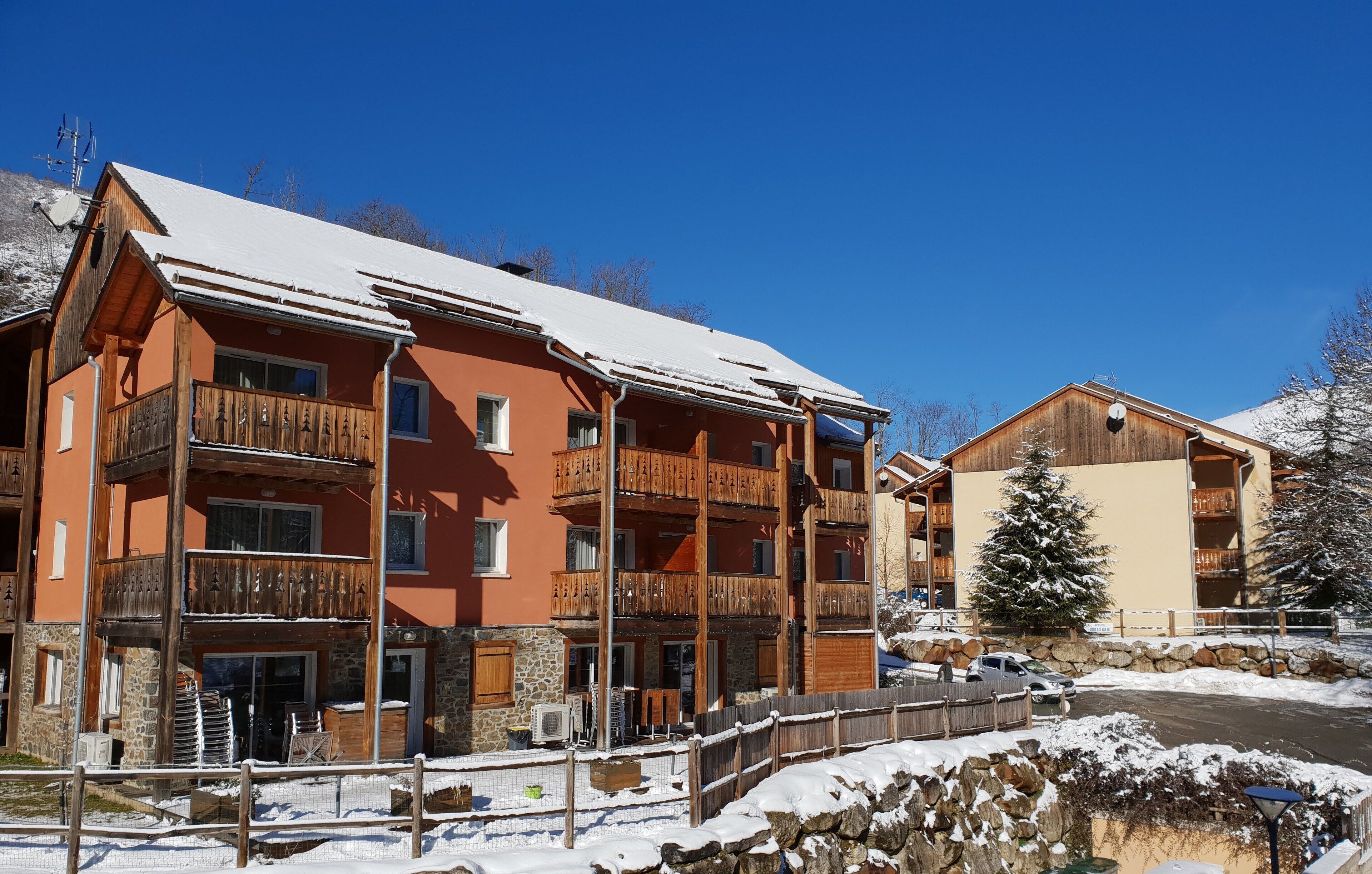 A multi-story hotel with wooden balconies and a stone facade.